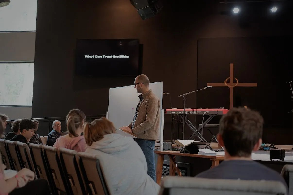 A man teaches a seated group in a church; a screen reads "Why I Can Trust the Bible.